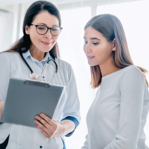 Smiling adult female doctor reporting medical results to young girl patient